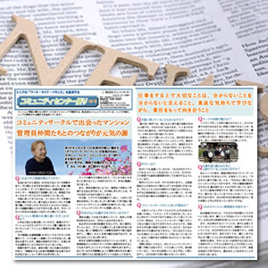 Two-page Japanese newsletter spread with multiple columns, photos, and headings, placed on a surface with a light wooden decorative object in the background.
