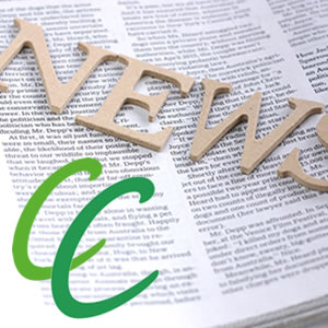 Wooden cursive 'News' lettering over a newspaper page, with a green stylized 'e' graphic in the foreground.